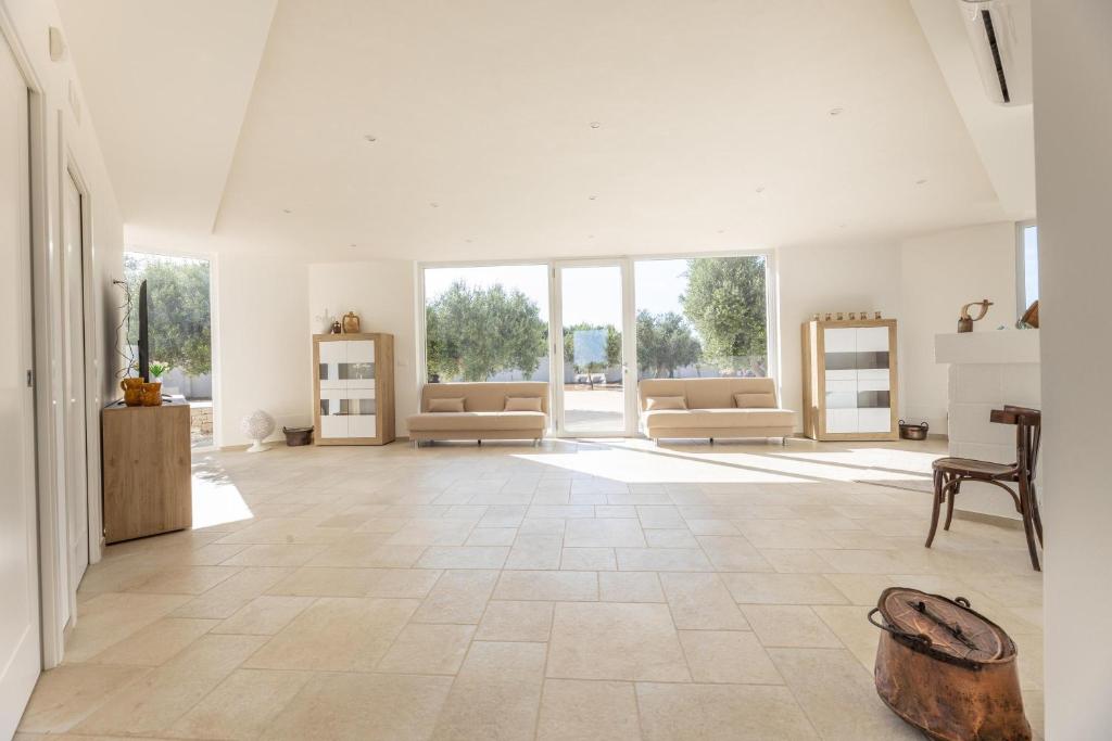 une grande pièce avec des murs blancs et de grandes baies vitrées dans l'établissement Tenuta Aspri, à Carovigno 127 autres photos