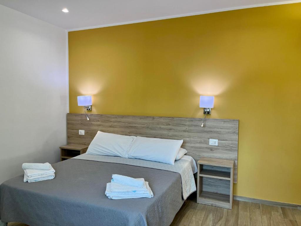 - une chambre avec un lit et un mur jaune dans l'établissement Salsedine Tropea Capo Vaticano, à Santa Domenica