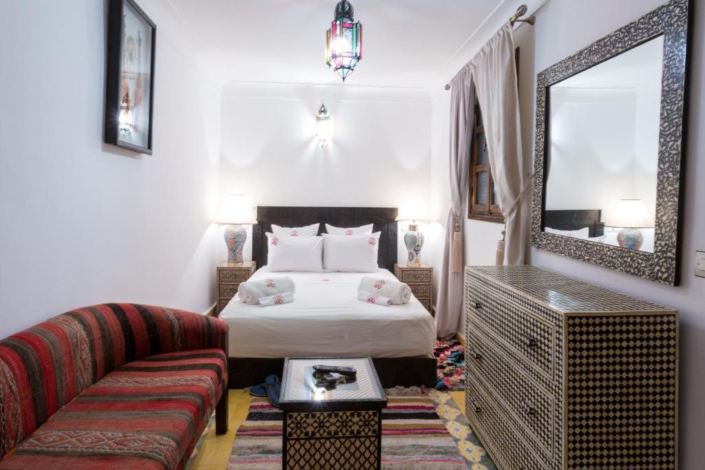 une chambre avec un lit, un canapé et un miroir dans l'établissement Riad Ikalimo 2, à Marrakech