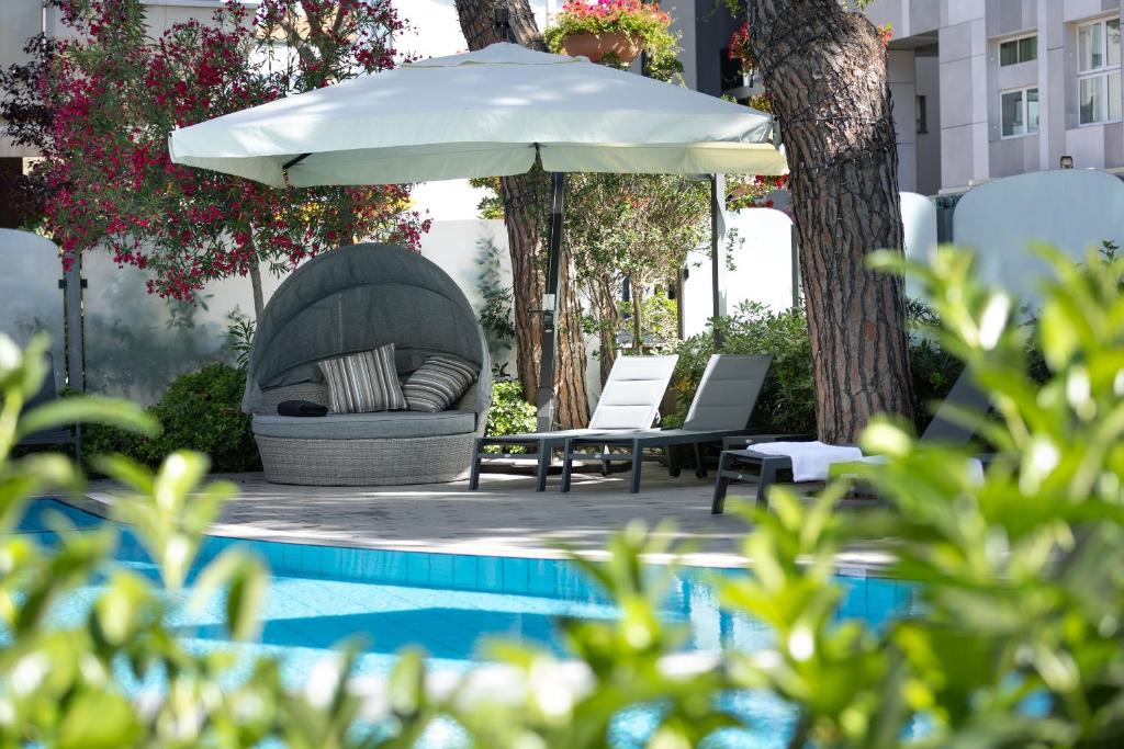 une terrasse avec un canapé et un parasol à côté d'une piscine dans l'établissement Hotel Adriatica con Piscina, à Riccione