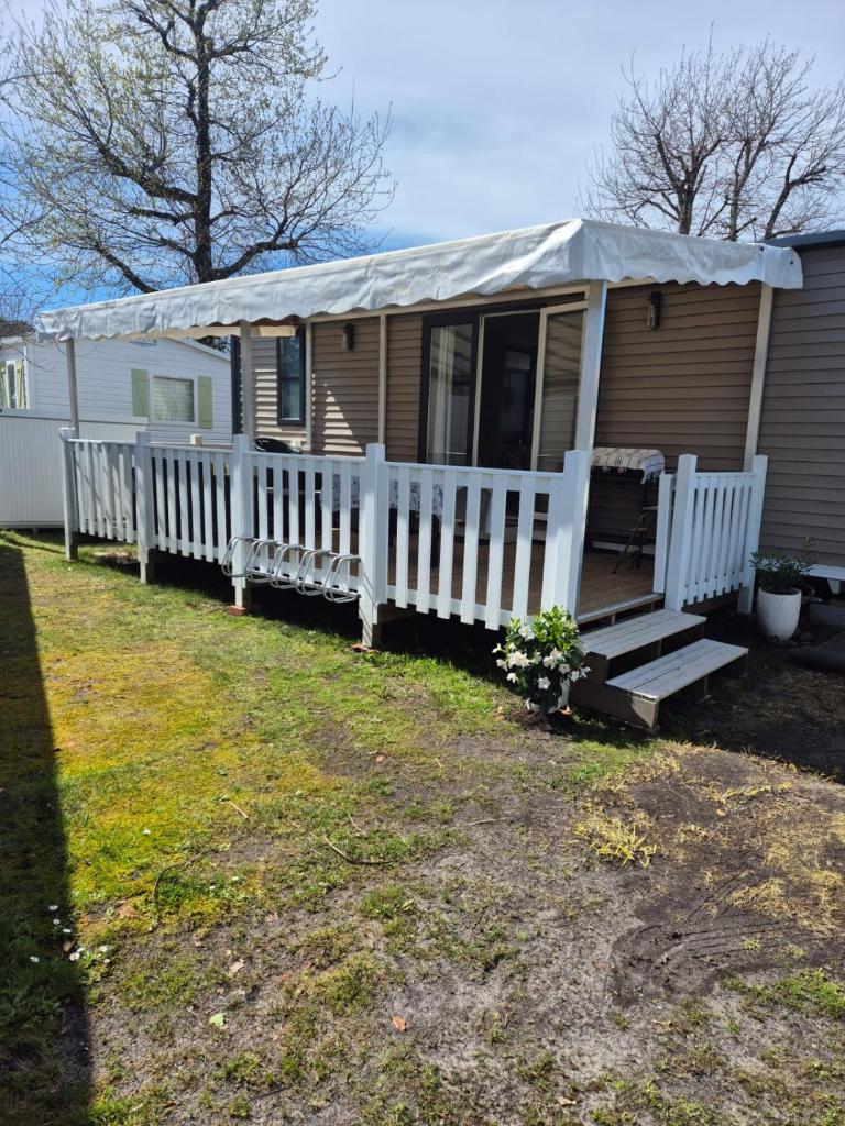 Ce mobile home dispose d'une terrasse couverte et d'une clôture blanche. dans l'établissement RB19 Nina, à Biscarrosse