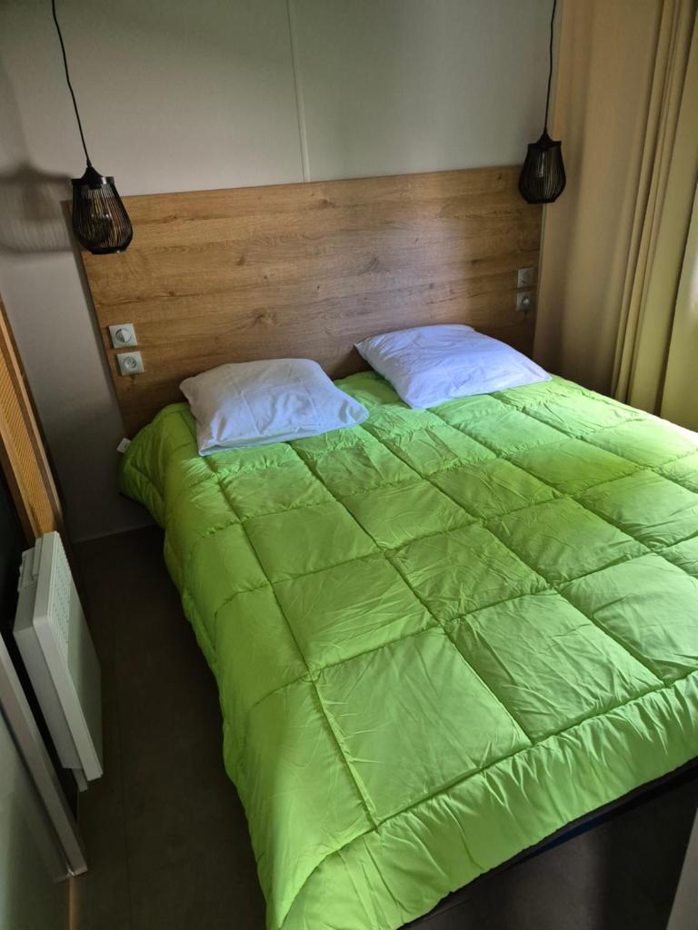 - un lit avec une couette verte et 2 oreillers dans l'établissement RB19 Nina, à Biscarrosse