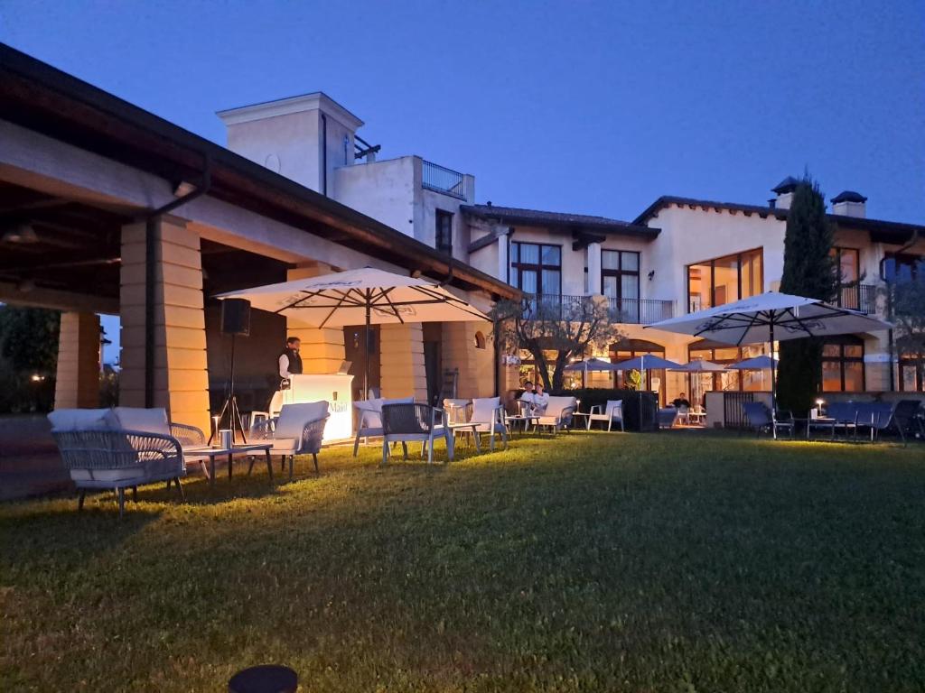 une pelouse avec des chaises et des parasols devant un bâtiment dans l'établissement Garda Resort Village I Borghi, à Peschiera del Garda