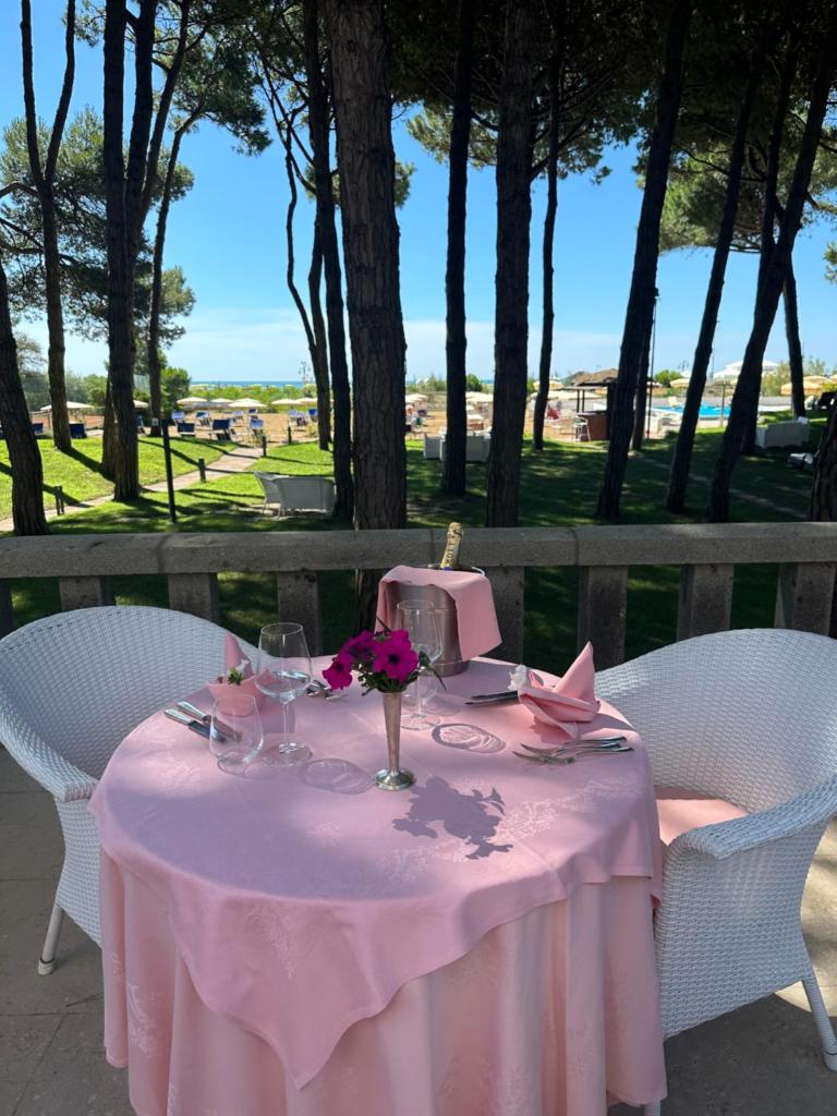 une table avec une toile de table rose et des fleurs sur elle dans l'établissement Hotel Beau Rivage Pineta, à Lido di Jesolo