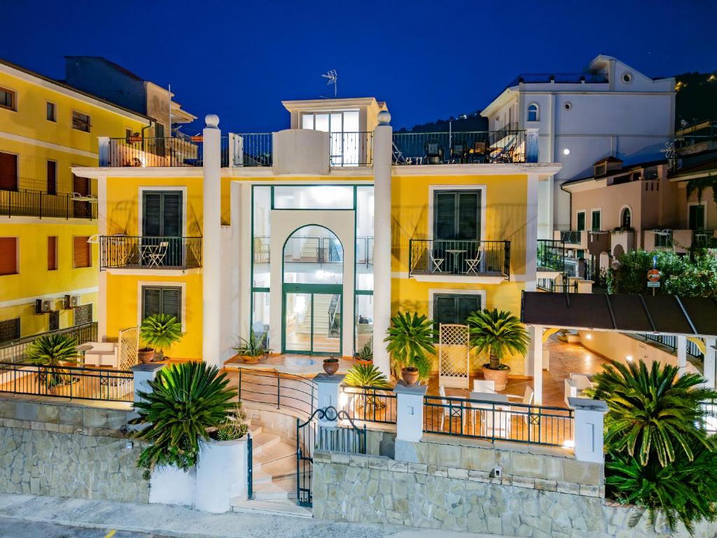 une maison jaune avec des palmiers devant dans l'établissement Hotel Villa Sirio, à Santa Maria di Castellabate