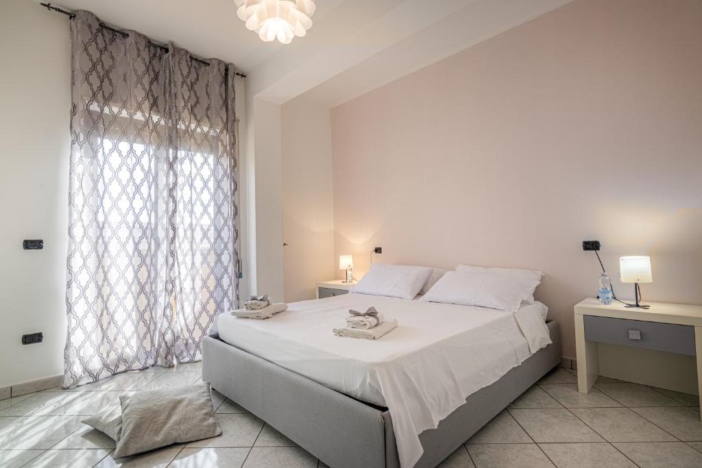 une chambre blanche avec un grand lit et une fenêtre dans l'établissement Home Le Castella, à Le Castella