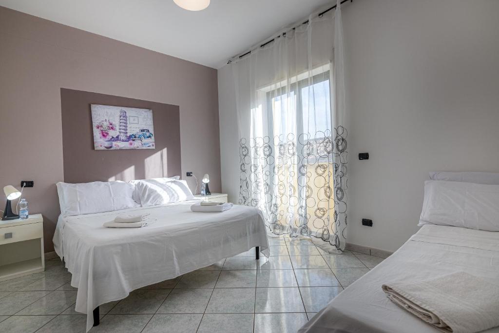 une chambre blanche avec deux lits et une fenêtre dans l'établissement Home Le Castella, à Le Castella