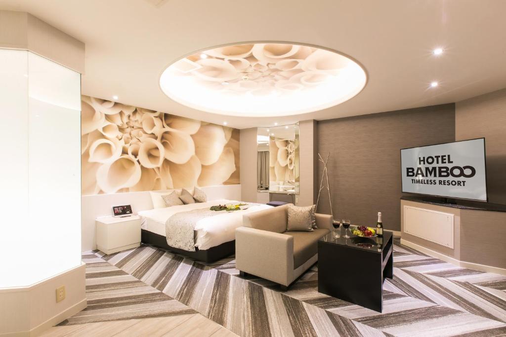 une chambre avec un lit, un canapé et une télévision dans l'établissement Hotel BAMBOO, à Iizuka
