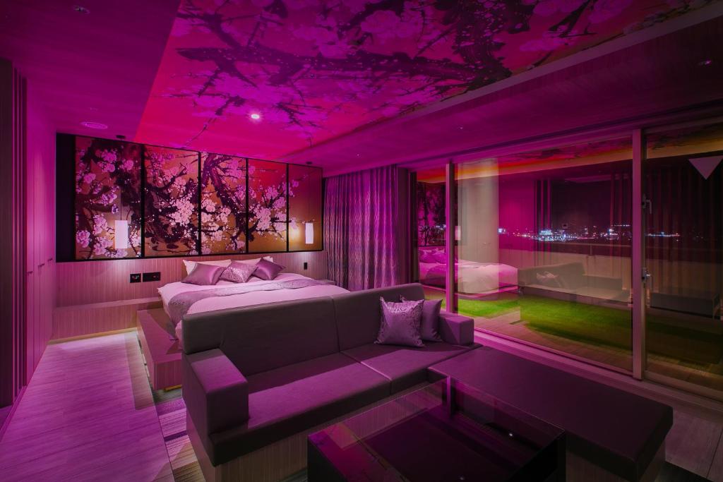 - une chambre violette avec un lit et un canapé dans l'établissement Hotel BAMBOO, à Iizuka