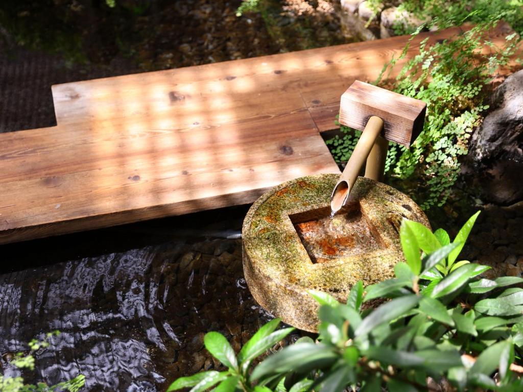 un banc en bois assis à côté d'un ruisseau avec un mortier dans l'établissement Hamanoyu, à Suwa