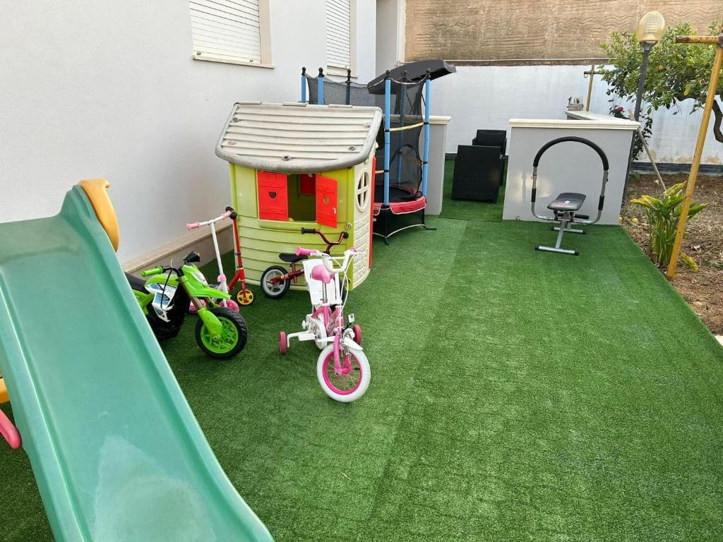 une aire de jeux avec un toboggan, des vélos et une maison dans l'établissement Lemon Gold, à Locogrande