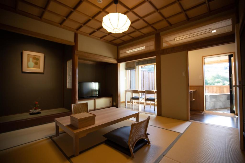 un salon avec une table, des chaises et une télévision dans l'établissement Chigira Jinsentei, à Shibukawa