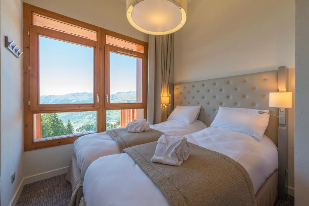 deux lits dans une chambre avec deux fenêtres dans l'établissement Appart'Hotel Prestige Odalys Eden, à Arc 1800