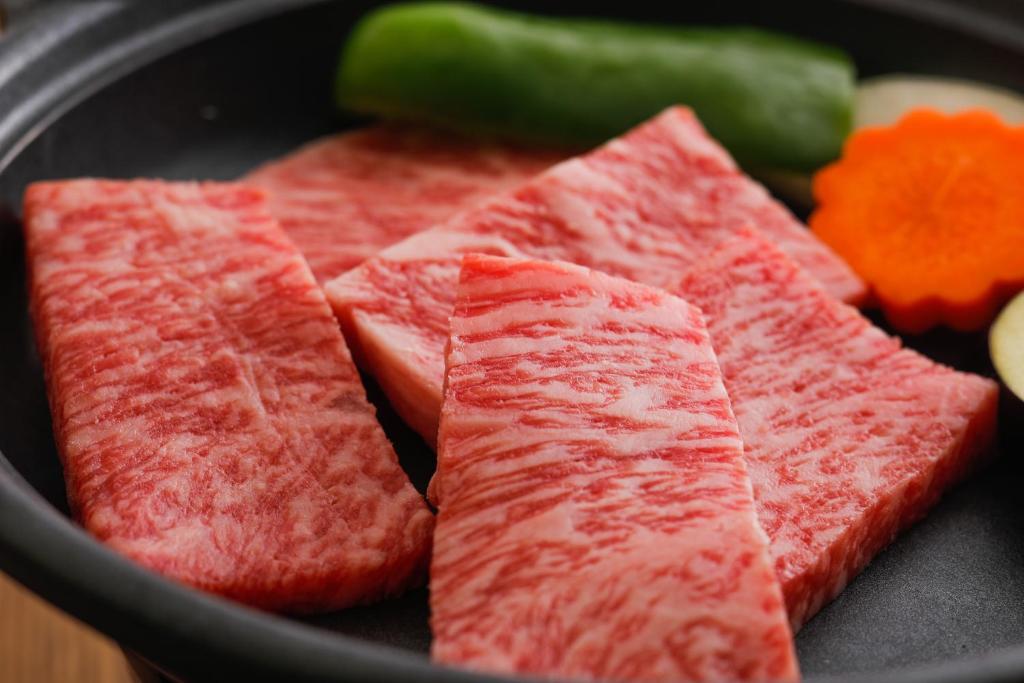 un tas de morceaux de viande dans une poêle avec des légumes dans l'établissement Tsuruya Ryokan, à Toyooka