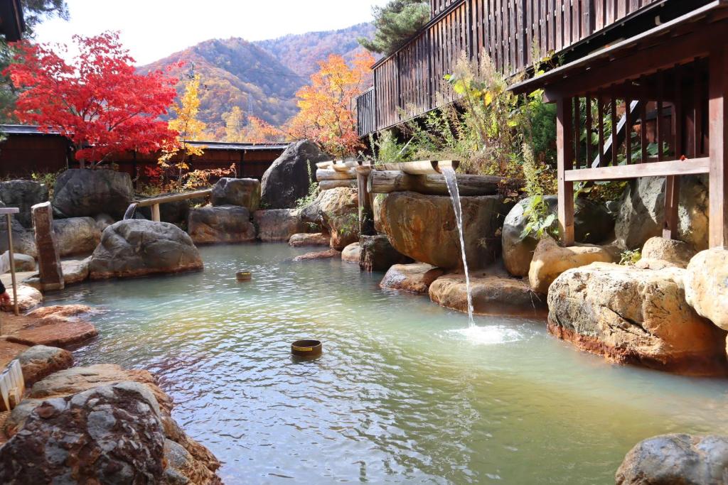 une piscine d'eau avec des rochers et une cascade dans l'établissement Hirayukan, à Takayama