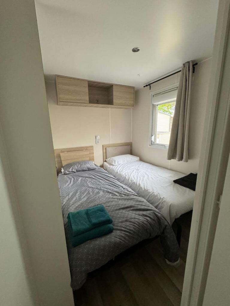 une petite chambre avec deux lits et une fenêtre dans l'établissement Mobil-Home, à Lège-Cap-Ferret 12 autres photos