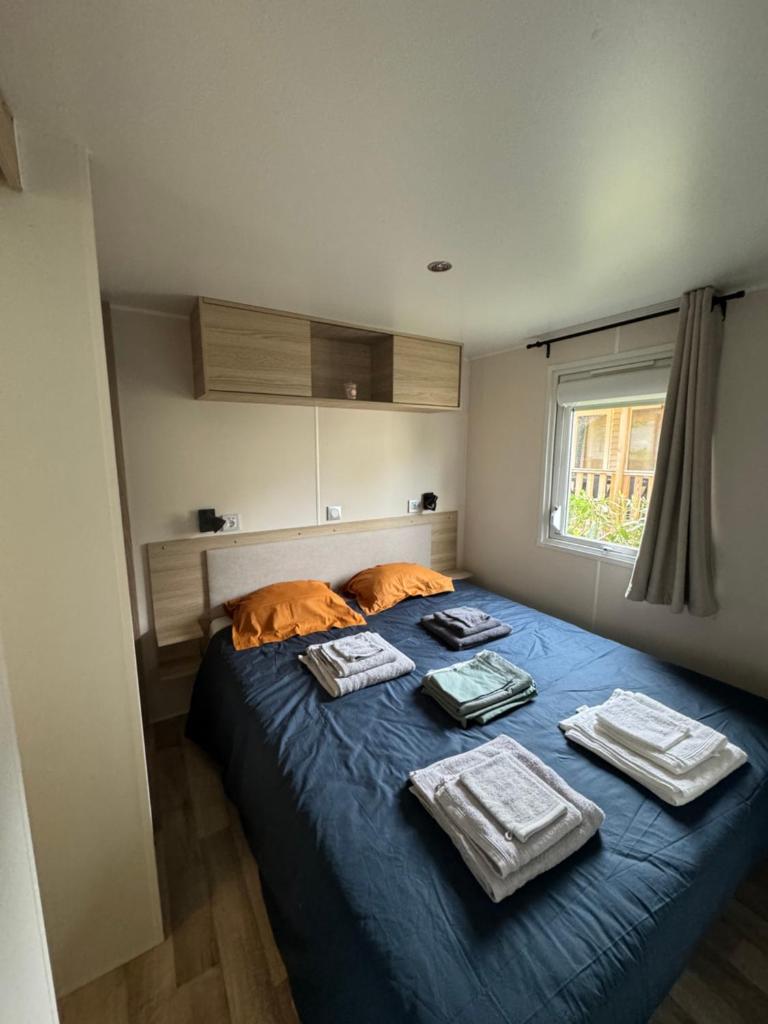 une chambre avec un lit bleu avec des serviettes dessus dans l'établissement Mobil-Home, à Lège-Cap-Ferret