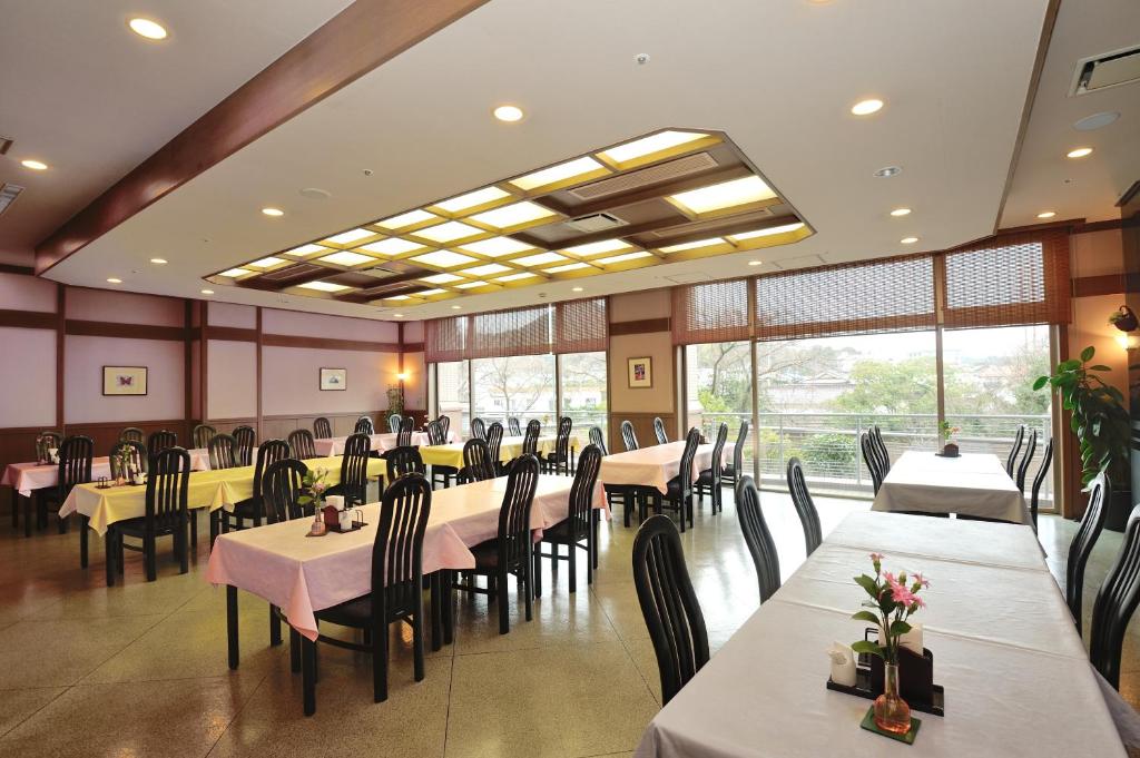 une salle à manger avec tables, chaises et fenêtres dans l'établissement Hotel Kasuien, à Ureshino