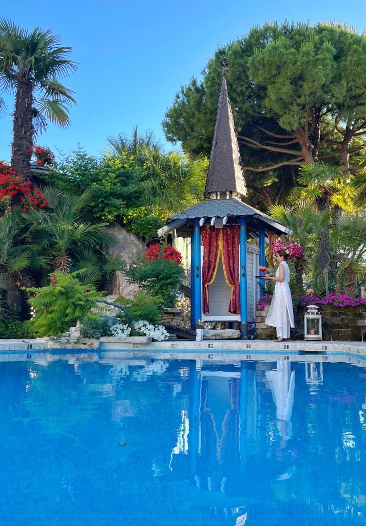 une femme debout à côté d'un kiosque à côté d'une piscine dans l'établissement Milton Boutique Hotel - Adults Only, à Lido di Jesolo