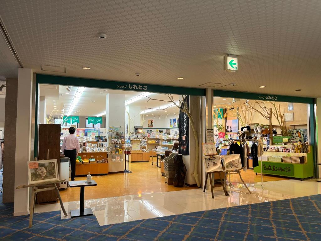 un magasin devant un centre commercial avec un homme dans le magasin dans l'établissement Hotel Shiretoko, à Shari