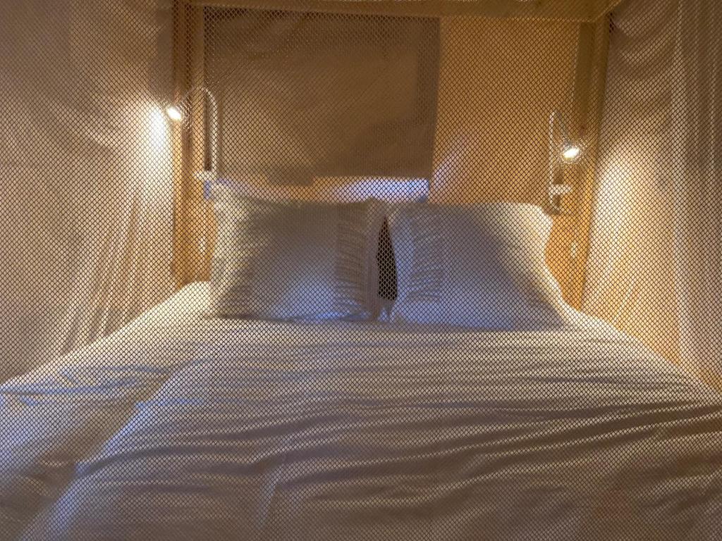 - une chambre dotée d'un lit avec des draps blancs dans l'établissement LODGE Champêtre Glamping, à Chadenac