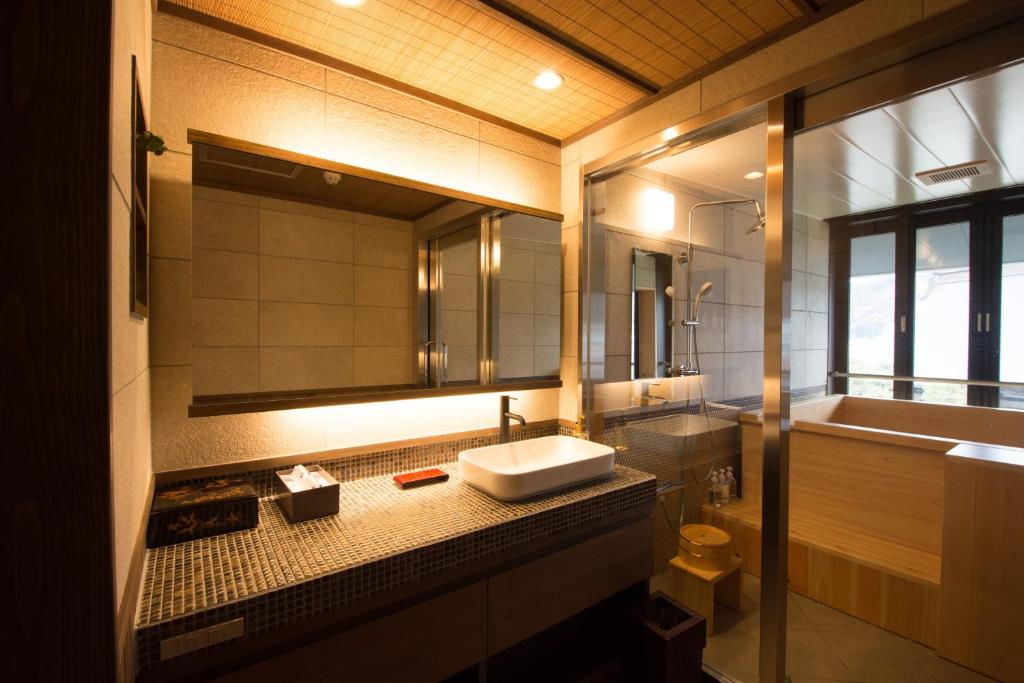 une salle de bain avec un lavabo et un grand miroir dans l'établissement Yatsusankan Over 6 years old, à Hida