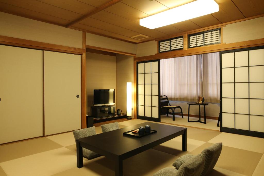 - un salon avec une table, un canapé et une télévision dans l'établissement 湯村温泉郷 御宿コトブキ, à Yumura