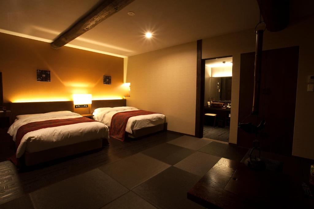 une chambre d'hôtel avec deux lits et une salle de bain dans l'établissement 湯村温泉郷 御宿コトブキ, à Yumura