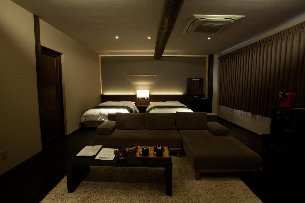 un salon avec un canapé et un lit dans l'établissement 湯村温泉郷 御宿コトブキ, à Yumura