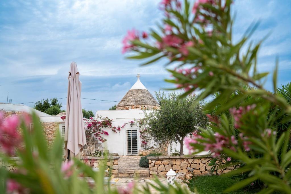 un parapluie et un bâtiment avec des fleurs roses dans l'établissement Trullo Vittoria Ostuni with private swimming pool, à Ostuni