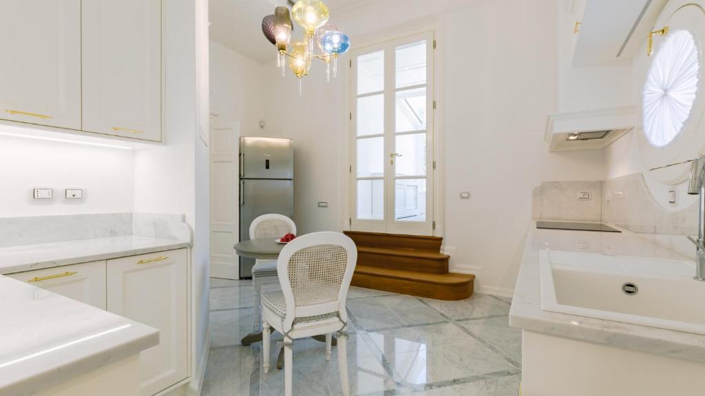 - une cuisine blanche avec deux chaises et un réfrigérateur dans l'établissement VILLA LA PERLA BIANCA 10, Emma Villas, à Empoli