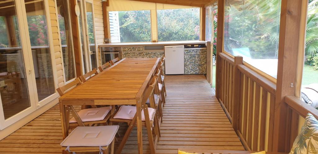 une terrasse couverte en bois avec une table et des chaises en bois dans l'établissement Camping les Cigales - Tikayan, au Muy