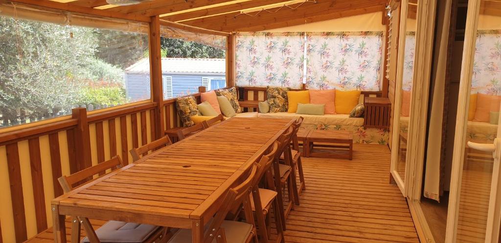une terrasse en bois avec une longue table et un canapé dans l'établissement Camping les Cigales - Tikayan, au Muy
