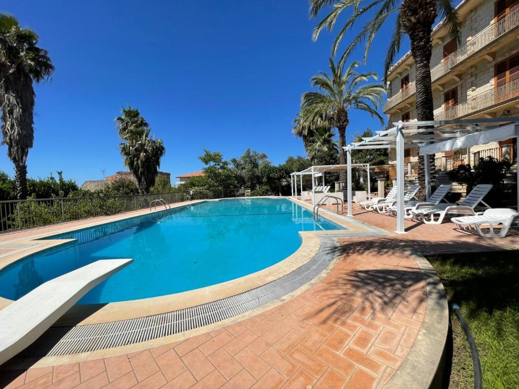une grande piscine avec chaises et palmiers dans l'établissement ALTA lux homeholiday stone, à Modica