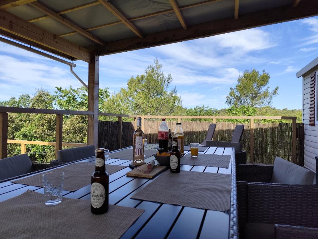 - une table en bois avec des bouteilles de vin sur la terrasse dans l'établissement MOBIL HOME 40M2 ECRIN DE VERDURE, à Rocbaron
