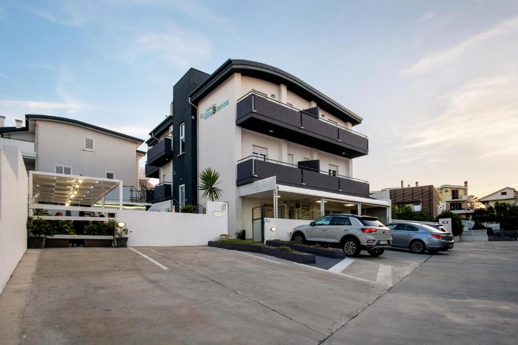 un bâtiment avec des voitures garées dans un parking dans l'établissement Hotel Villa Bianca, à San Salvo