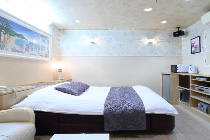 une chambre avec un lit et un canapé dans l'établissement ホテルミントハウス&ウイング, à Mihama