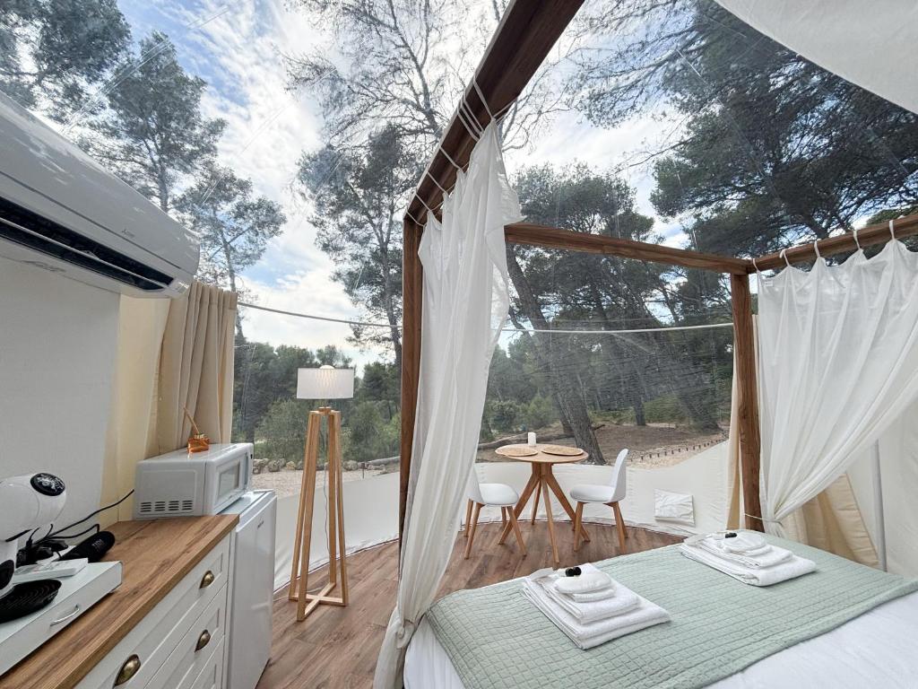 - une chambre dotée d'une grande fenêtre avec une table et des chaises dans l'établissement La Bulle des Pins, à Istres