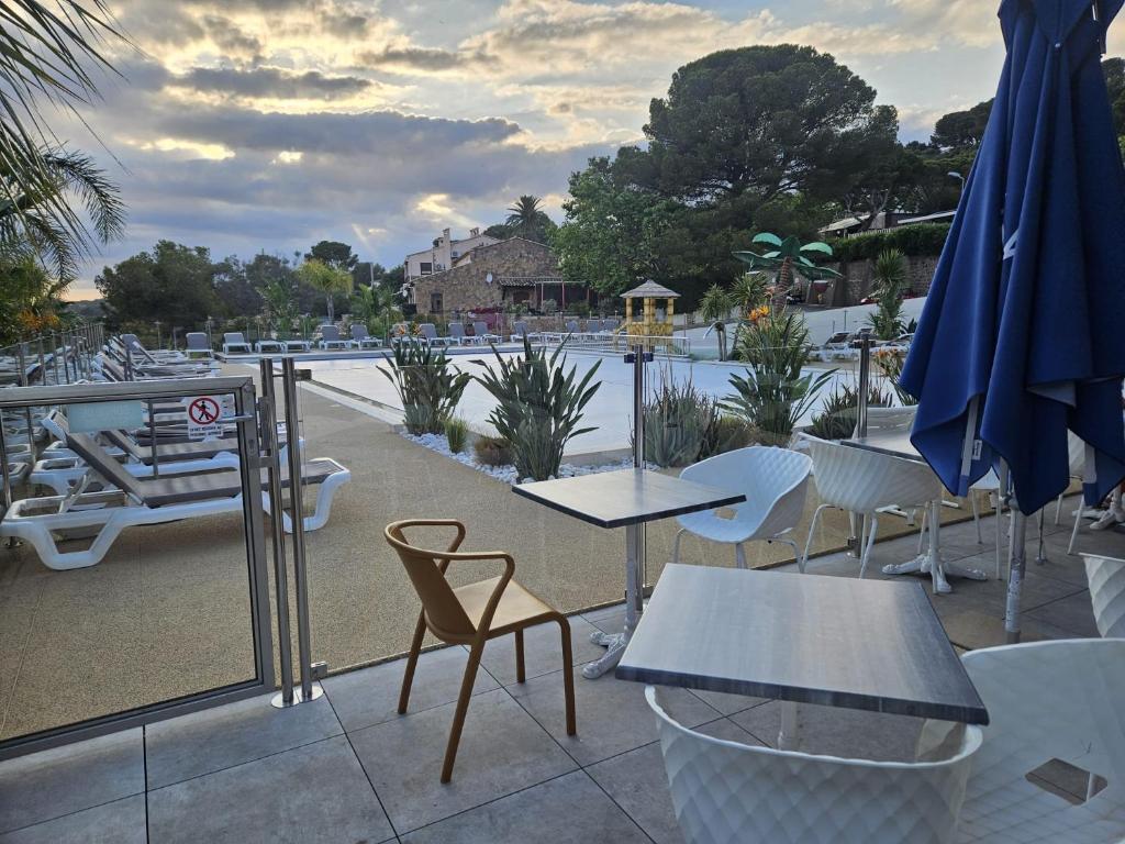un patio avec tables, chaises et un parasol dans l'établissement Voltaire, à Saint-Raphaël