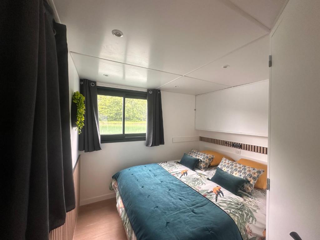 une chambre avec un lit avec une couette bleue et une fenêtre dans l'établissement House Boat avec SPA naviguant en Champagne, à Mareuil-sur-Ay