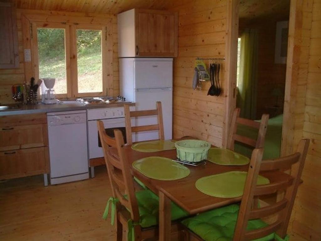 une cuisine avec une table et des chaises dans une cabine dans l'établissement L'Ecrin de nature, à La Bachellerie