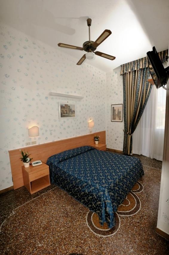 une chambre avec un lit et un ventilateur de plafond dans l'établissement Hotel Miramare, à Ladispoli