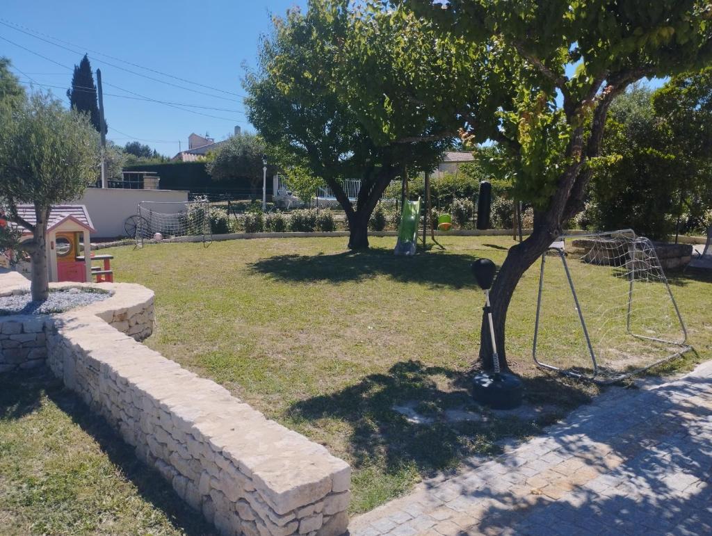 un parc avec un arbre et un mur en pierre dans l'établissement Gîte chez l'habitant indépendant "La villa des ocres", à Gargas
