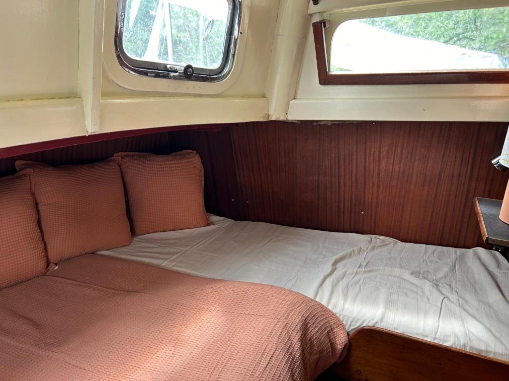 - un lit à l'arrière d'une chambre avec fenêtre dans l'établissement Séjour insolite sur un bateau, à Louveciennes