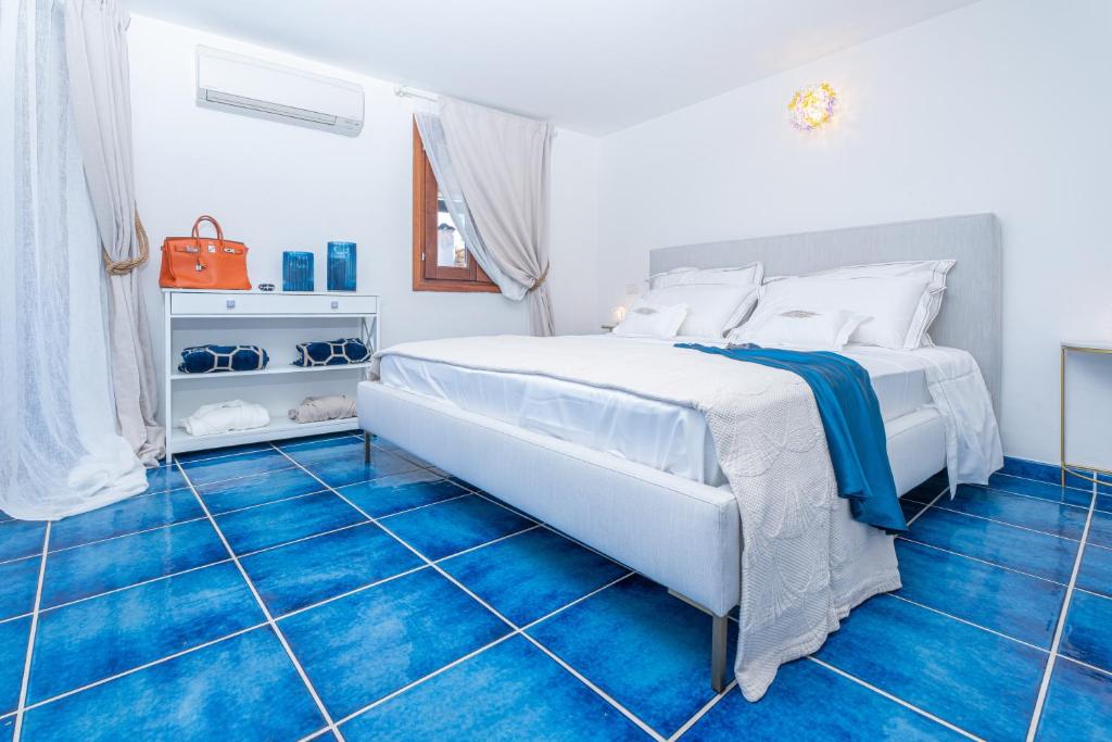- une chambre dotée d'un lit blanc et de carrelage bleu dans l'établissement Villa Graya, à Porto Istana