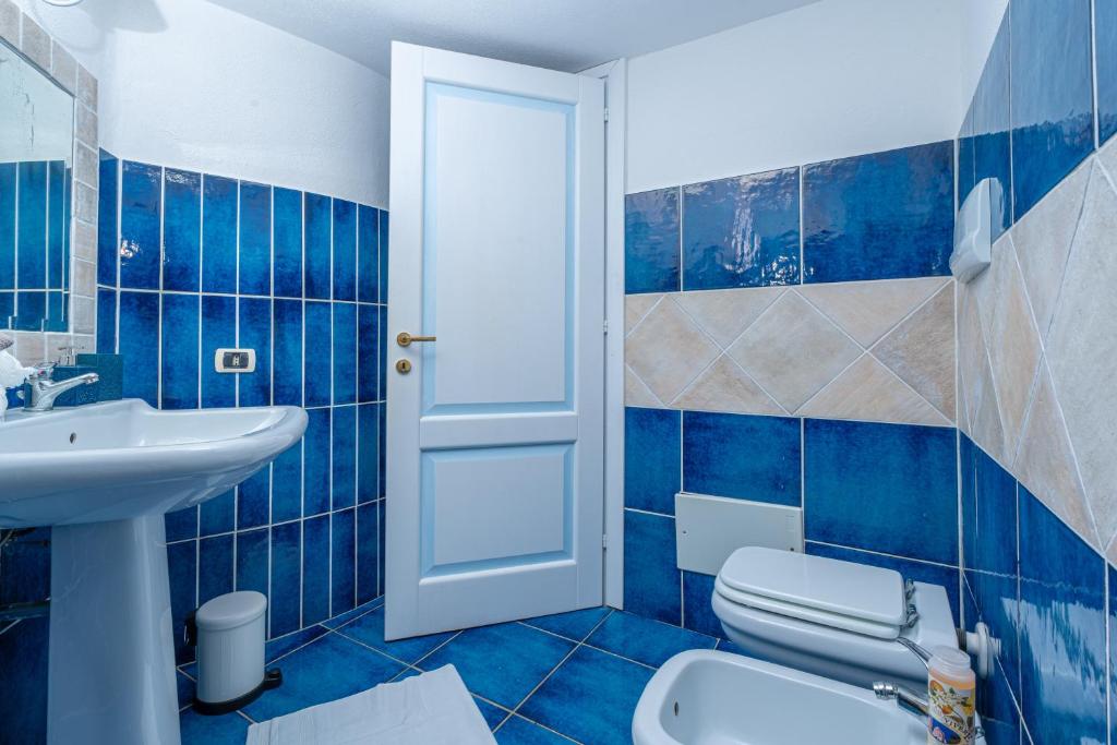 La salle de bains est pourvue de carrelage bleu, de toilettes et d'un lavabo. dans l'établissement Villa Graya, à Porto Istana 91 autres photos