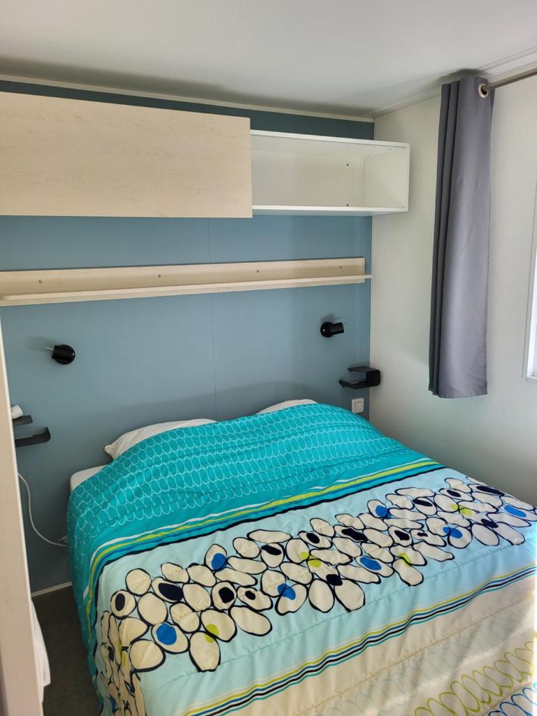 une chambre avec un lit avec une tête de lit bleue et un lit sidx sidx sidx dans l'établissement Mobil home 4 personnes climatisé, à Hyères