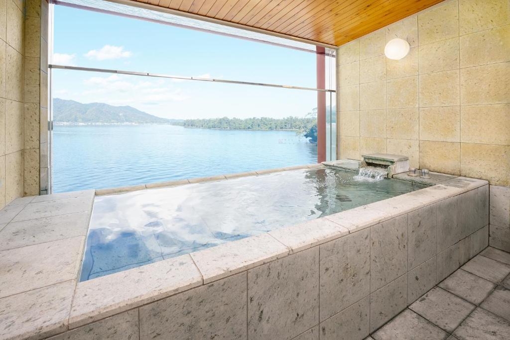une baignoire jacuzzi avec vue sur l'eau dans l'établissement Amano Hashidate Hotel, à Miyazu