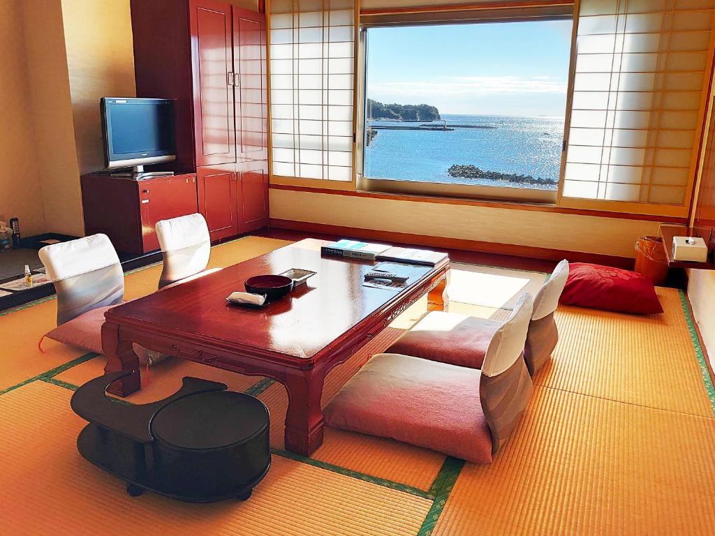 - un salon avec une table, des chaises et une grande fenêtre dans l'établissement Mikazuki Sea-Park Hotel Katsuura, à Katsuura