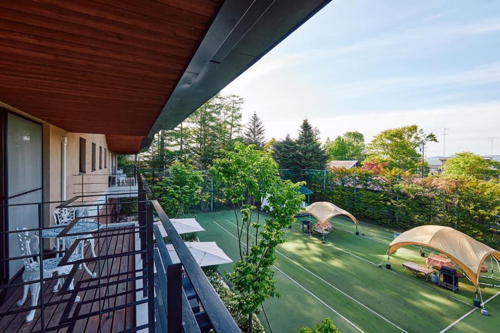 un balcon extérieur avec un court de tennis avec deux parasols dans l'établissement IKOI Villa, à Karuizawa